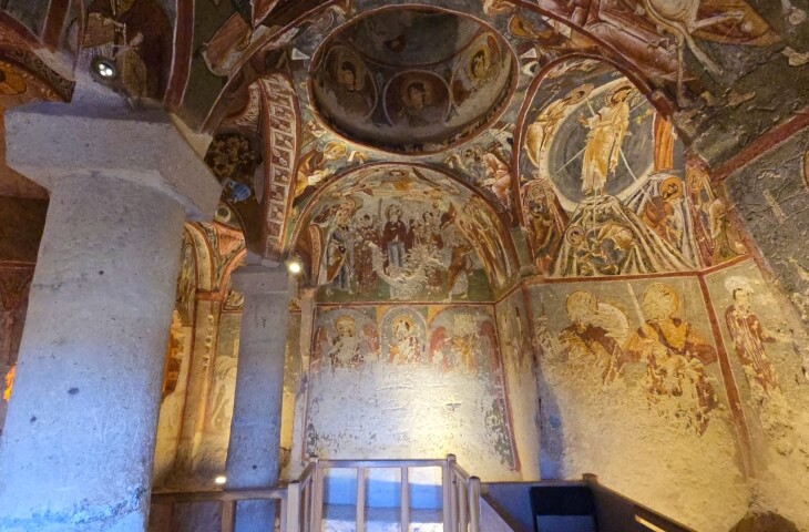 Göreme Açık Hava Müzesi’ndeki Çarıklı Kilise’nin iç mekanı; fresklerle kaplı duvarlar, sütunlar ve kubbe detayları görülüyor.